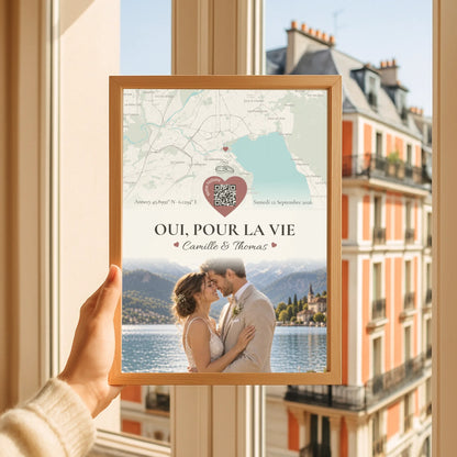 Affiche souvenir de mariage encadrée et tenue devant une fenêtre lumineuse.