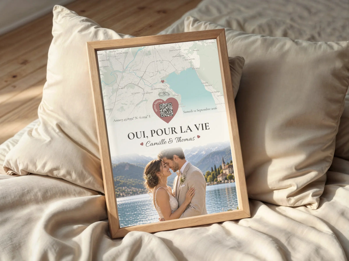 Affiche de mariage personnalisée dans un cadre posé sur un lit aux tons clairs.