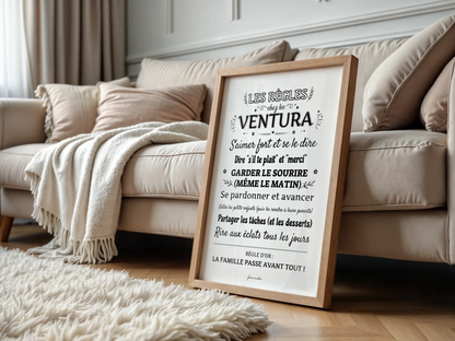 Affiche « Les règles chez les Ventura » encadrée, posée devant un canapé dans un salon lumineux.