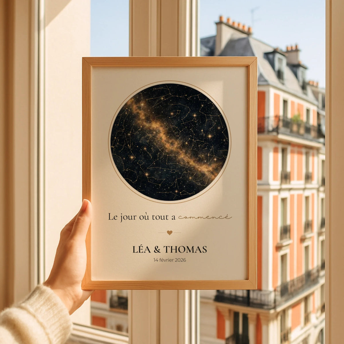 Affiche ciel étoilé personnalisée noir et or dans un cadre en bois tenu devant une fenêtre
