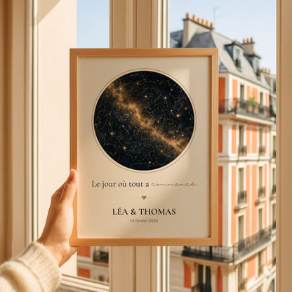 Affiche ciel étoilé personnalisée noir et or dans un cadre en bois tenu devant une fenêtre
