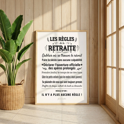 Affiche Les règles de la retraite encadrée, dans un décor en bois éclairé par le soleil, à côté d’une plante.
