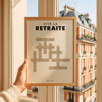 Affiche « Vive la retraite » aux lettres beiges entrecroisées, tenue devant une fenêtre dans un cadre en bois clair.